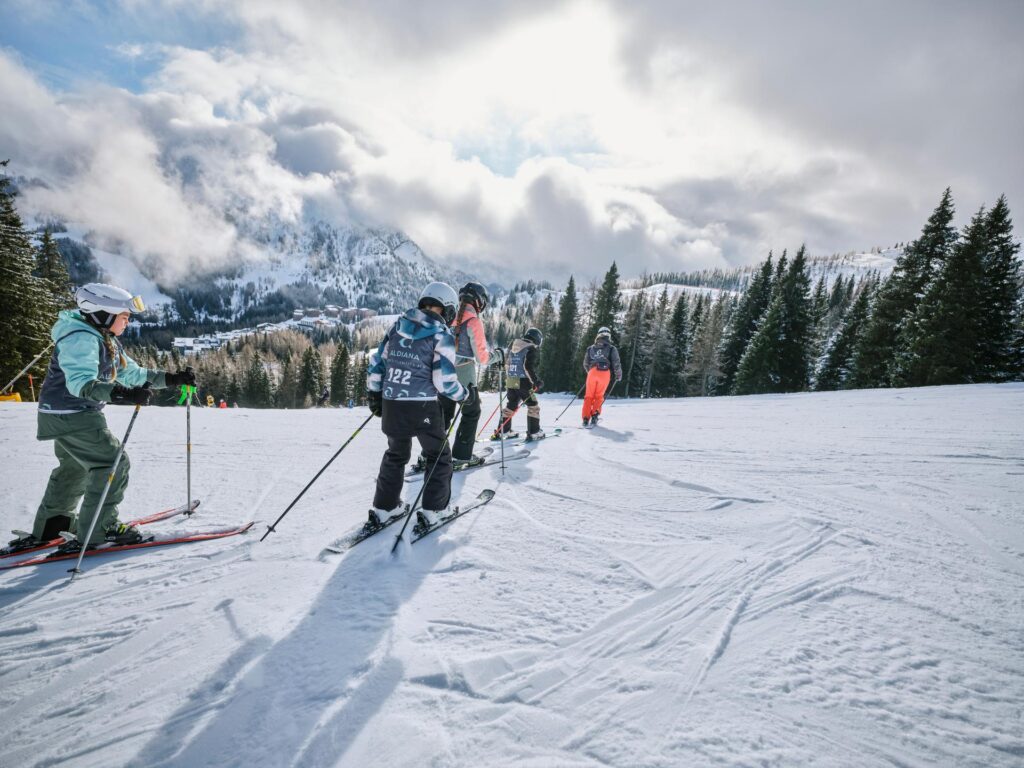 Skianfänger fahren gemeinsam mit der Skilehrerin den Hang runter.