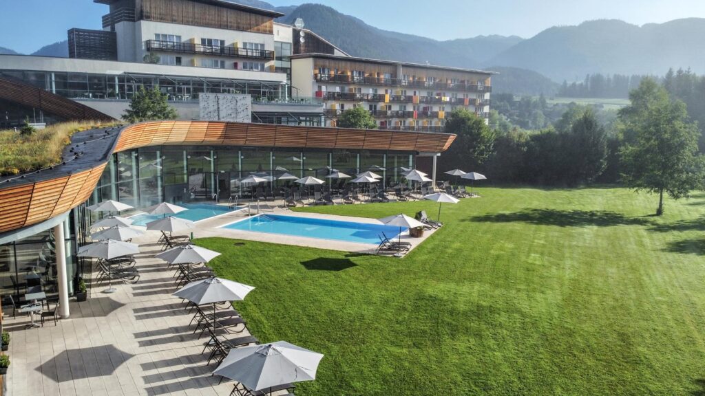 Blick auf den Aldiana Club Salzkammergut, im Hintergrund ist der Grimming zu sehen. Vorne sieht man den Poolbereich des Sauna Bereiches. 