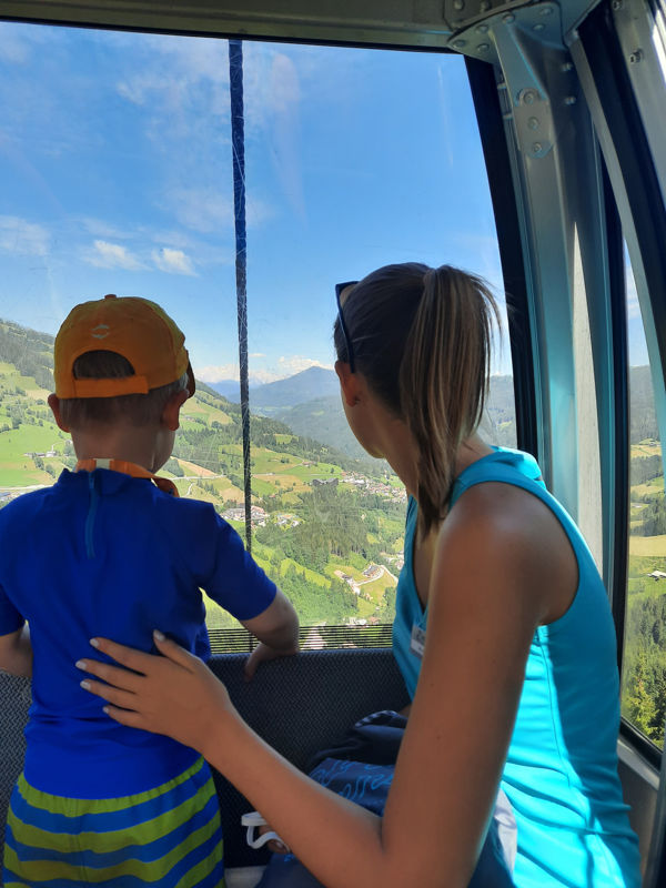 Aldiana-Animateurin Melina genießt mit kleinem Gast beim Kinderurlaub in Österreich den Ausblick aus der Gondel übers Tal