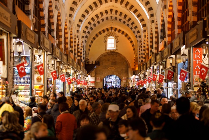 Menschen im Basar von Istanbul mit türkischen Flaggen und Gewölbedecke.