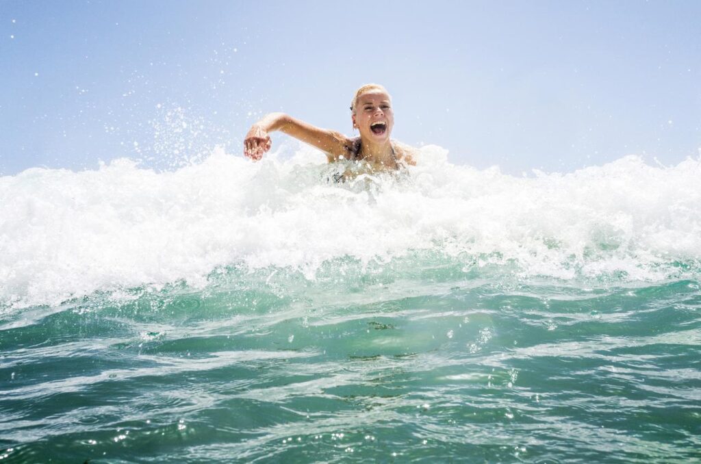 Frau paddelt auf dem Surfbrett zur nächsten Welle