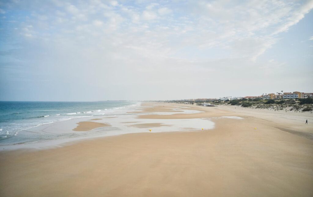 Blick auf einen wunderschönen langen Sandstrand, wo du in der Elternzeit ausgiebige Spaziergänge während deiner Reise unternehmen kannst. 