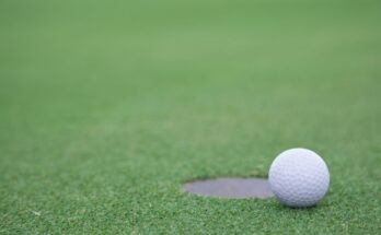 Golfball liegt nahe dem Loch auf grünem Rasen
