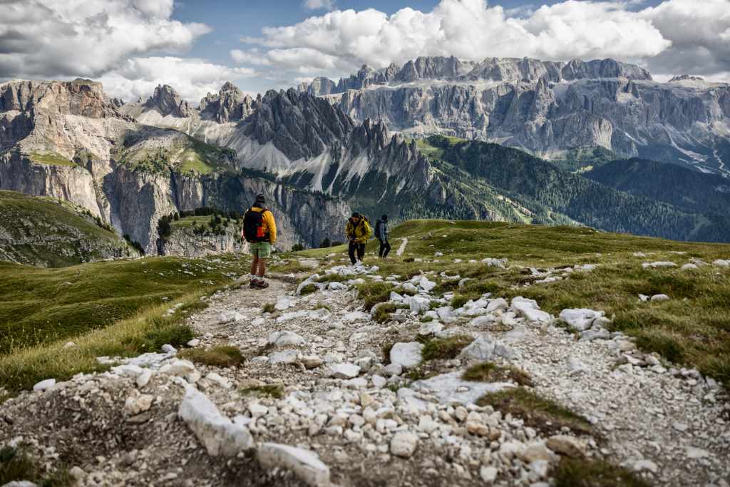 Wanderer auf steinigem Pfad mit beeindruckendem Bergpanorama im Hintergrund.