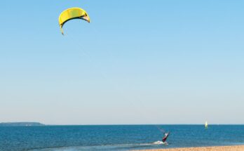 Kitesurfer mit gelbem Schirm fährt entlang der Küste.