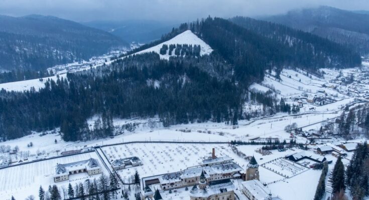 Luftaufnahme eines verschneiten Dorfes in den Bergen.