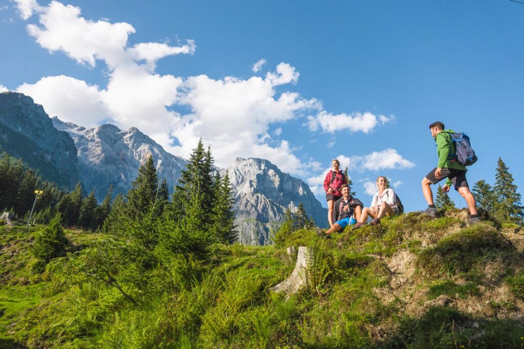 Österreich eignet sich als tolles Reiseziel für Wanderer im Oktober. Hier sieht man wie gerade Wanderer eine Rast am Fuße des Berges machen. 