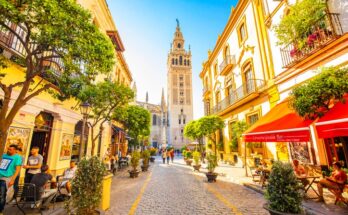 Gasse in Sevilla mit Blick auf die Giralda und sonnigen Fassaden.