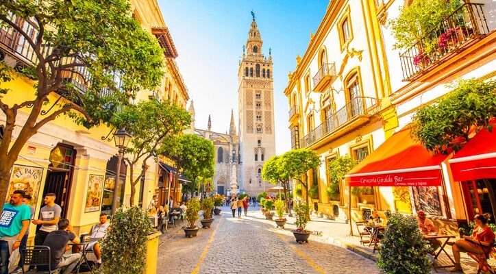 Gasse in Sevilla mit Blick auf die Giralda und sonnigen Fassaden.