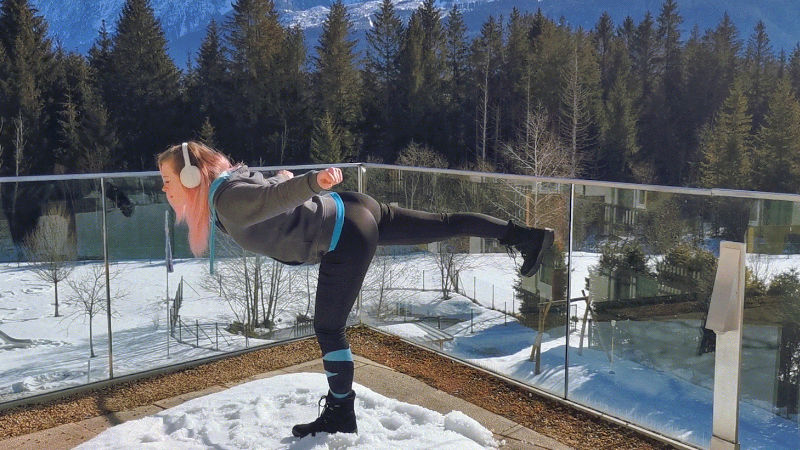 Frau macht Standwaage als Skigymnastik-Übung aus dem Stand