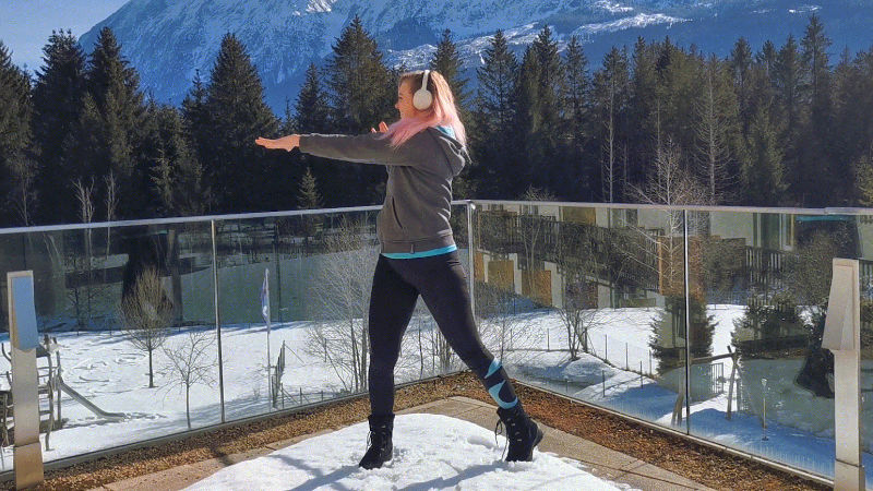 Eine Frau macht einen Twist als Skigymnastik-Übung zum Aufwärmen