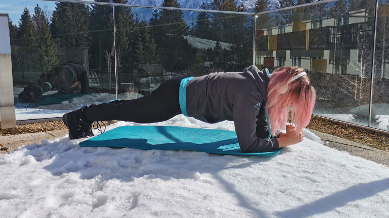 Frau macht Unterarmstütz bei den Skigymnastik-Übungen auf dem Boden