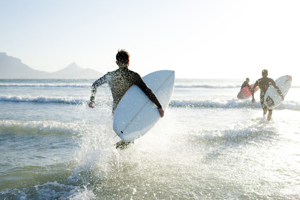 Surfer rennen ins Meer. Surfen kann man sehr gut in Andalusien. 