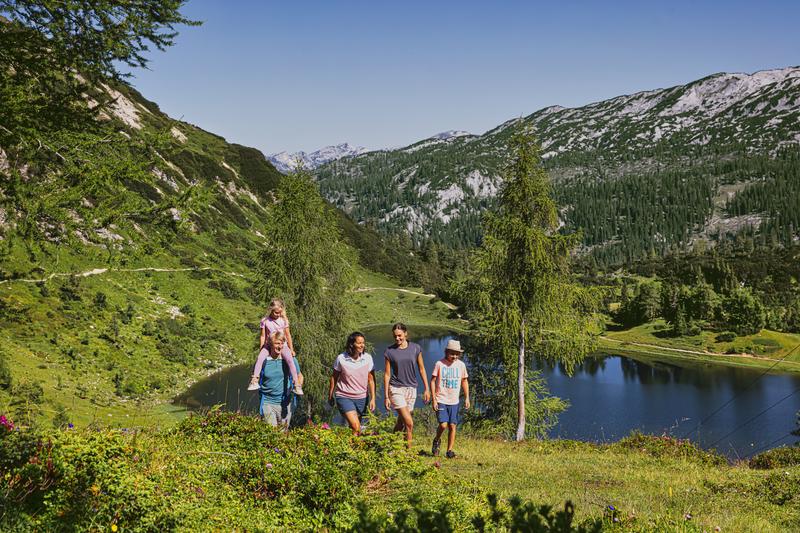 Wandern mit der ganzen Familie entlang eines Sees im Sommer in Österreich. 